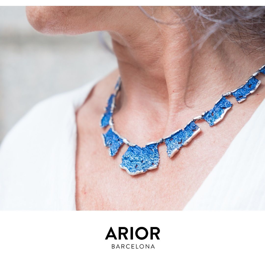 Een blauwe juwelenketting om iemands nek. Wit bovenstuk, lichte achtergrond.
