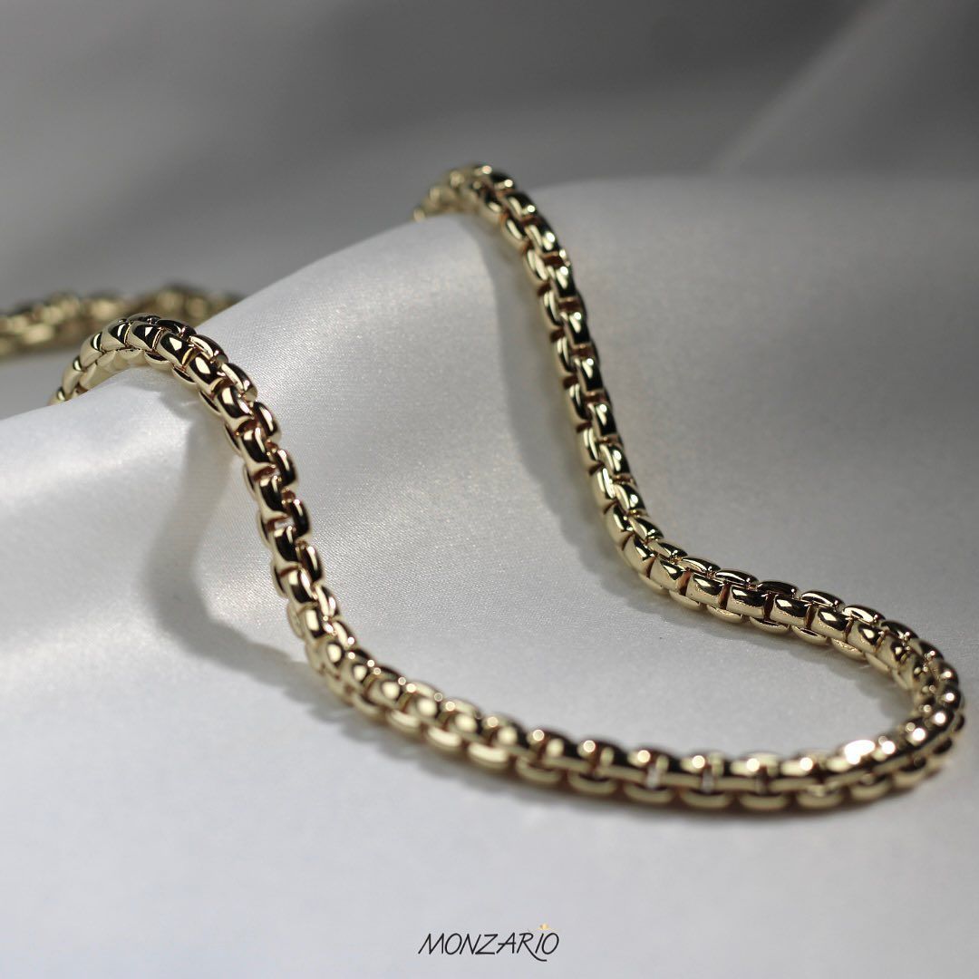 Gouden ketting rustend op witte satijnen stof.