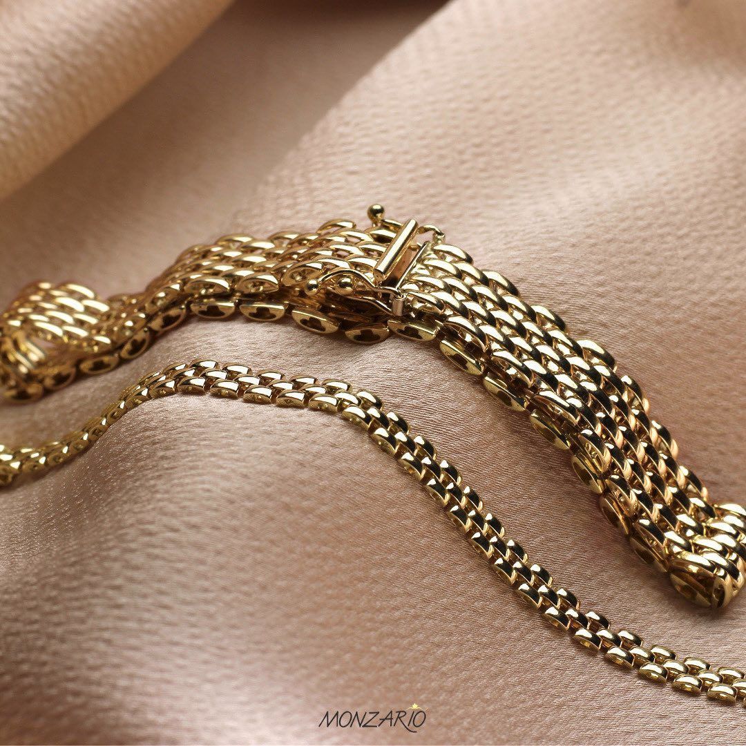 Gouden ketting van beige, gestructureerde stof. De sluiting is zichtbaar.