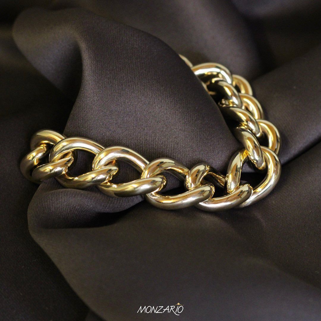 Gouden schakelarmband op zwarte stof.