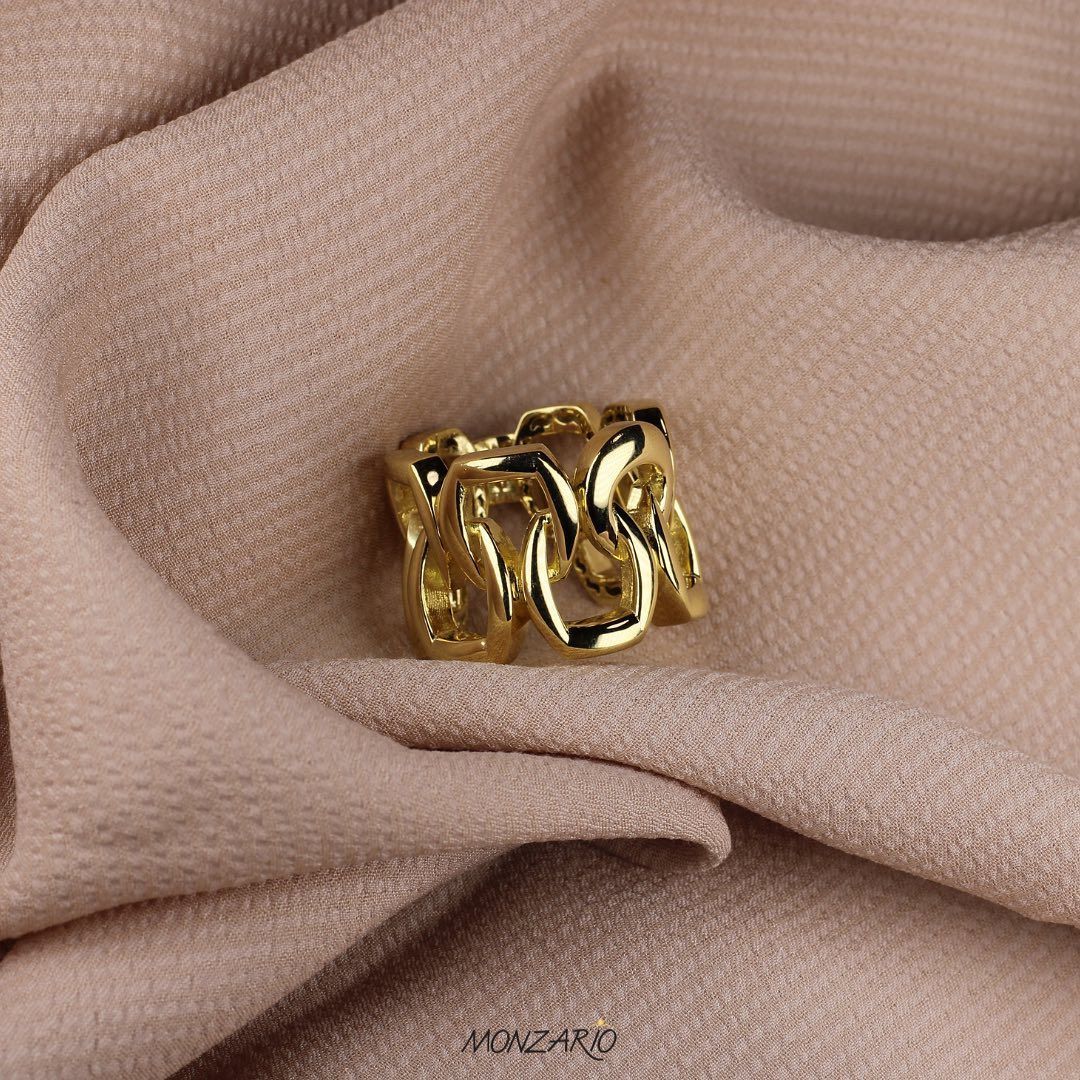 Gouden schakelring op beige stof.