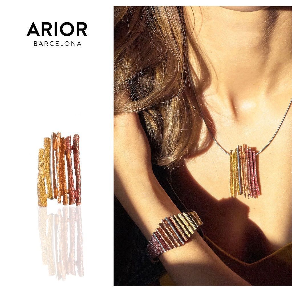 Ari of Barcelona sieraden: ring, armband en ketting met kleurrijke, verticale strepen; vrouw draagt ketting en armband.