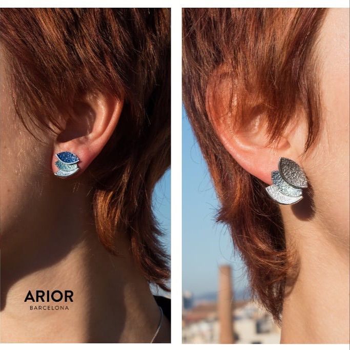 Vrouw met zilveren oorbellen in de vorm van een blad. Zonlicht accentueert haar kastanjebruine haar. Het stadsgezicht van Barcelona is zichtbaar.