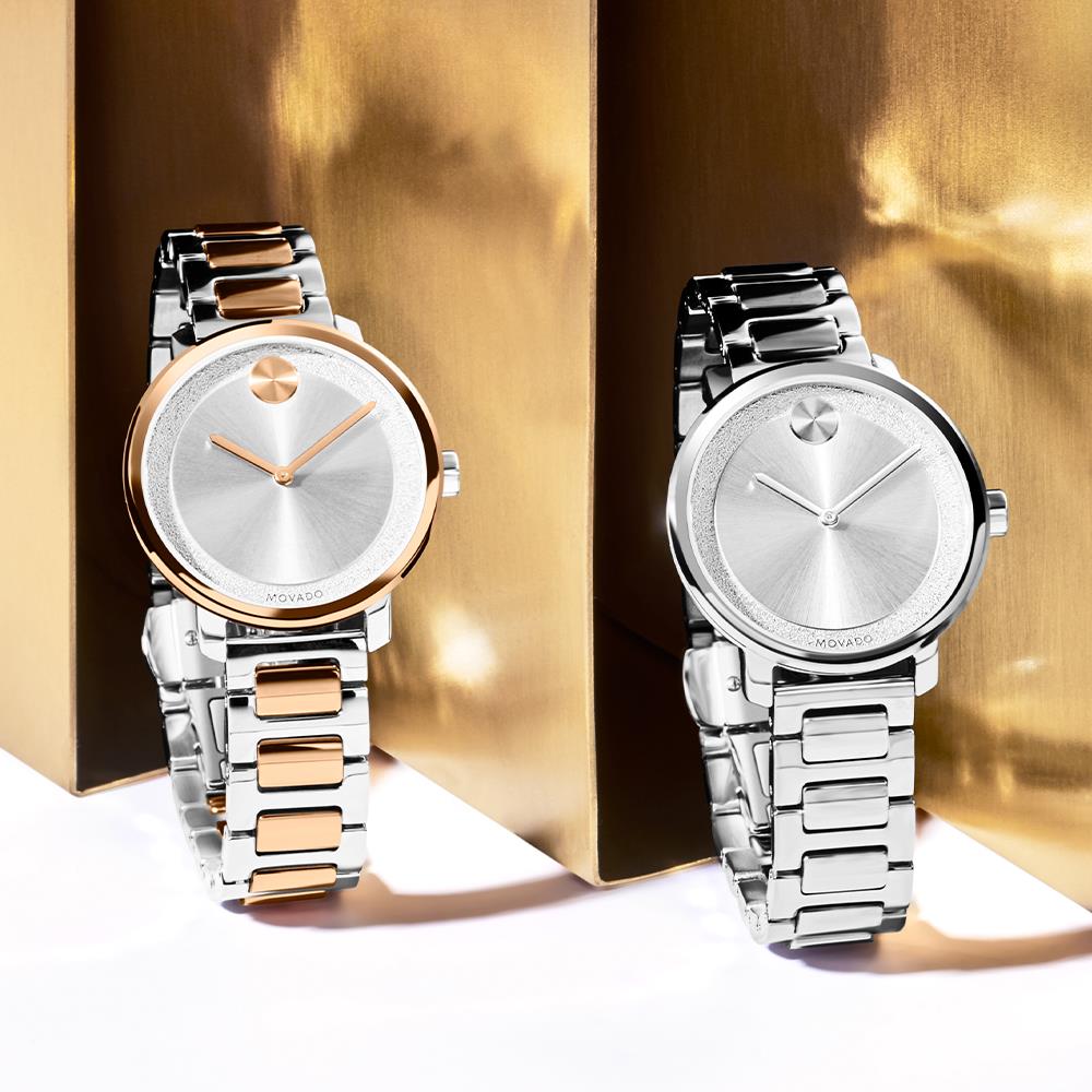 Twee Movado-horloges op een gouden achtergrond. Eén heeft een roségouden lunette en bandaccenten.