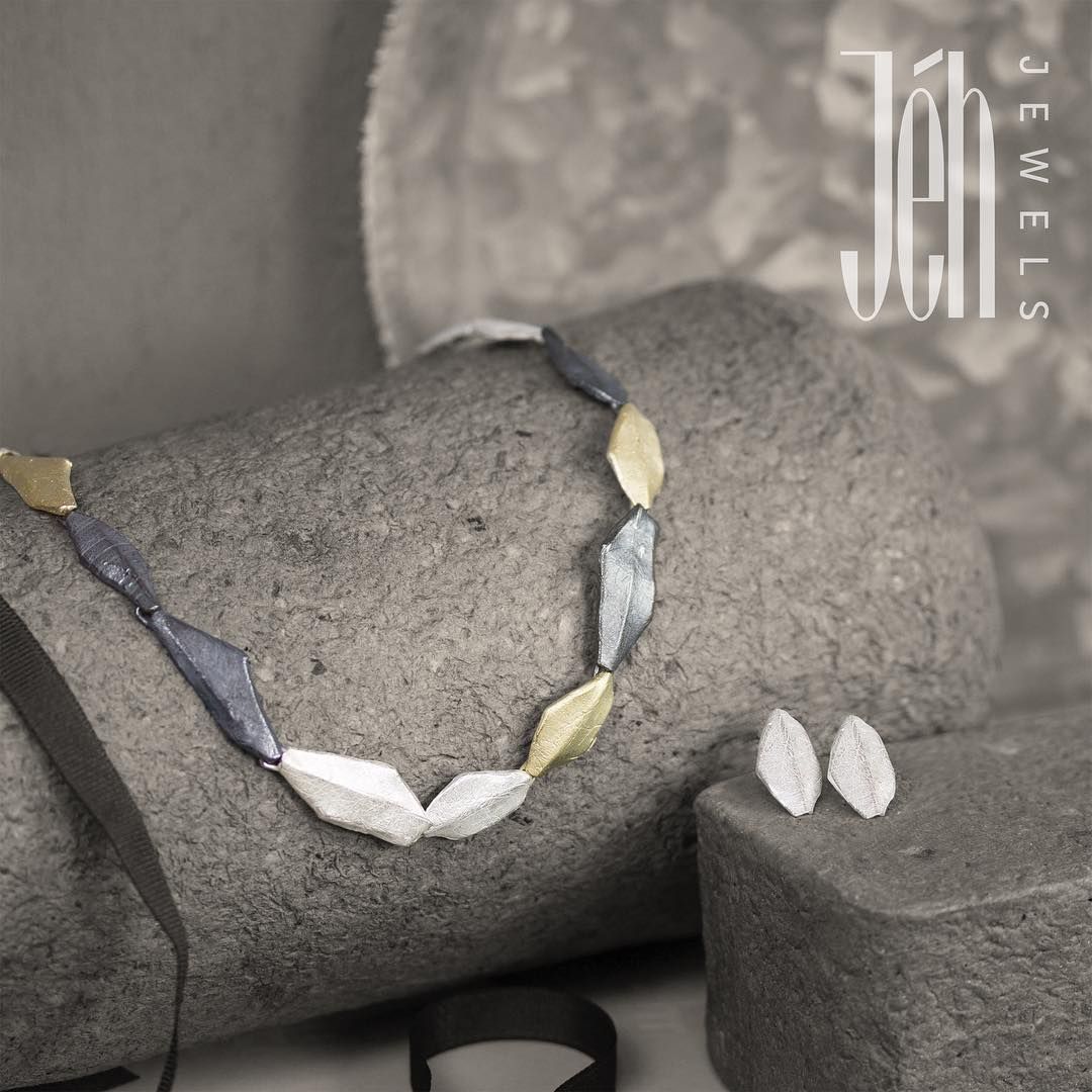Ketting en oorbellen met grijze steen en zwart lint. Sieraden van zilver, goud en blauw.