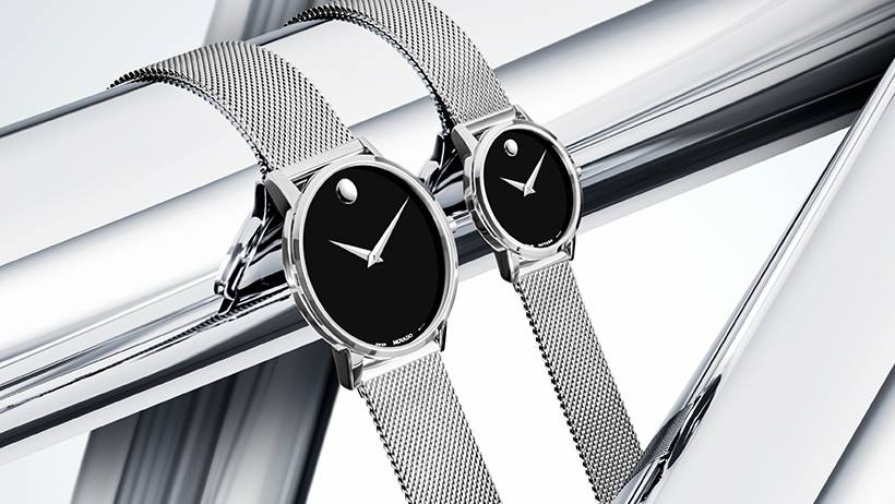 Twee Movado horloges met zwarte wijzerplaten en zilveren banden.