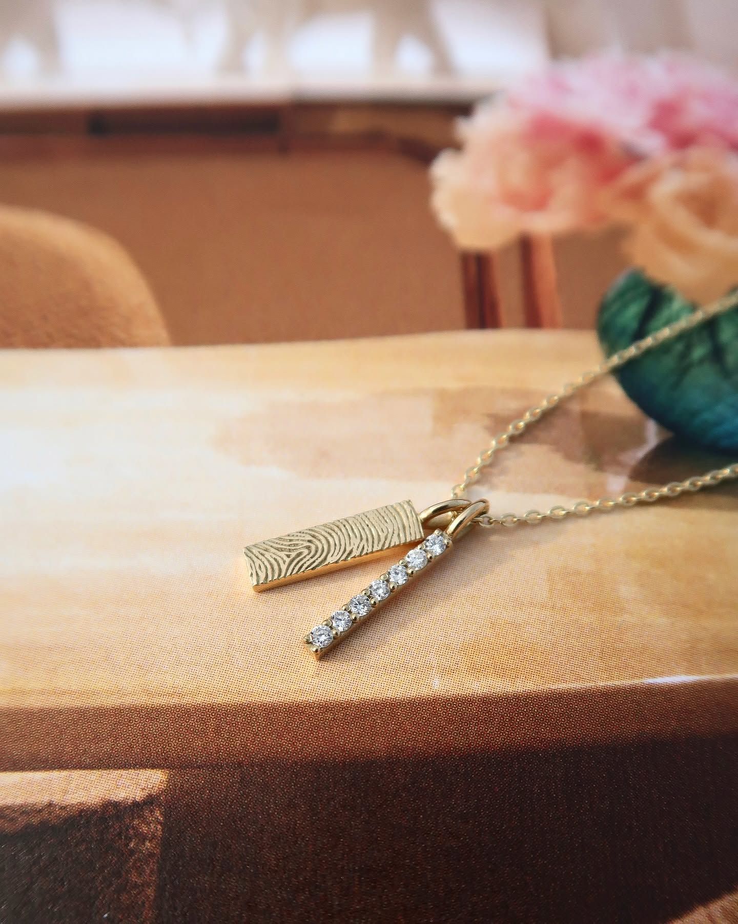Gouden ketting met ovale hanger bezet met kleine steentjes op een wit shirt.