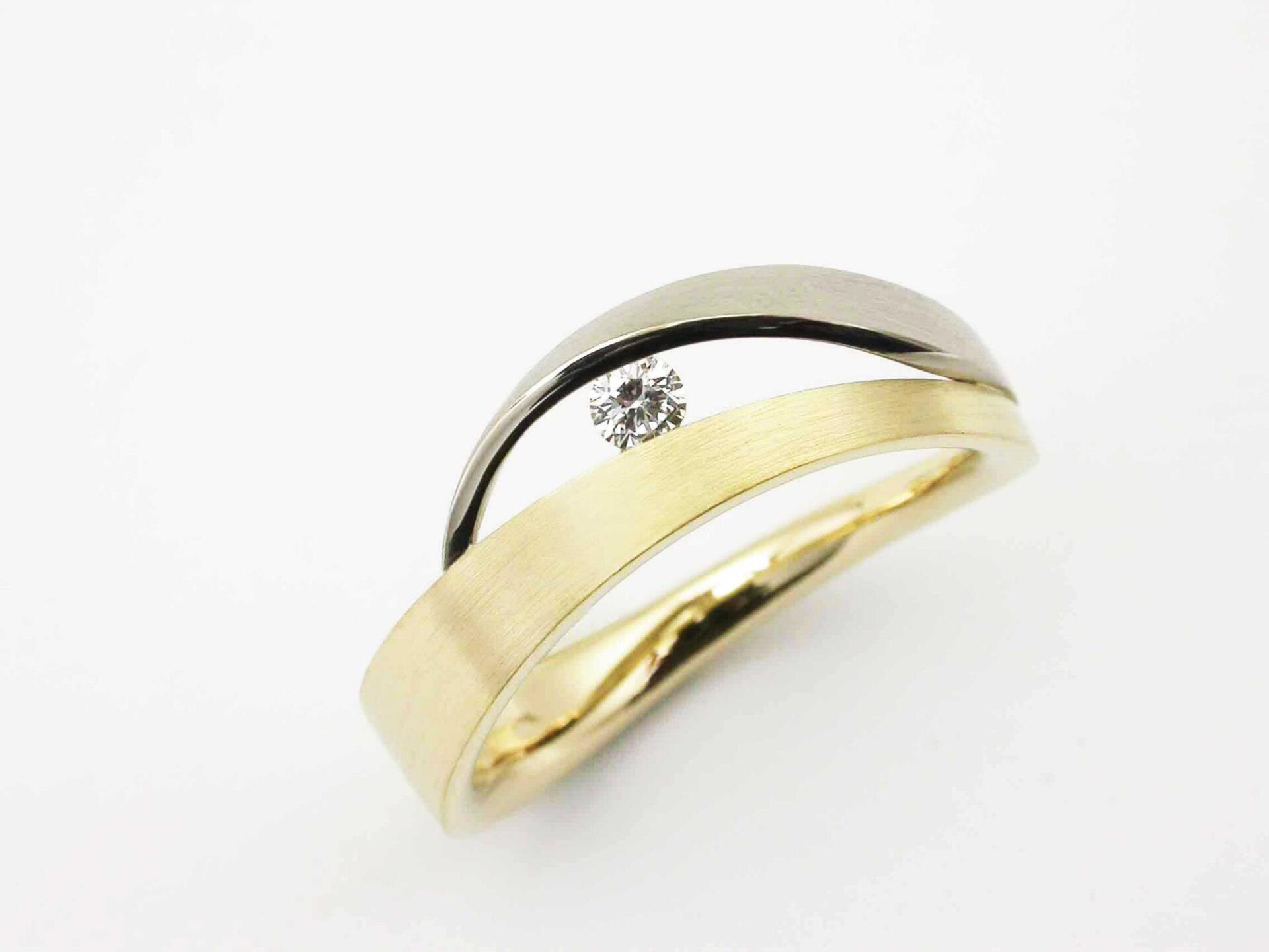 Tweekleurige gouden ring met een diamant op een witte achtergrond.
