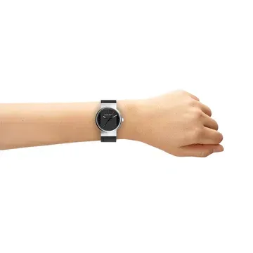 Een horloge met een zwarte wijzerplaat en een zilveren band om de pols van een persoon.