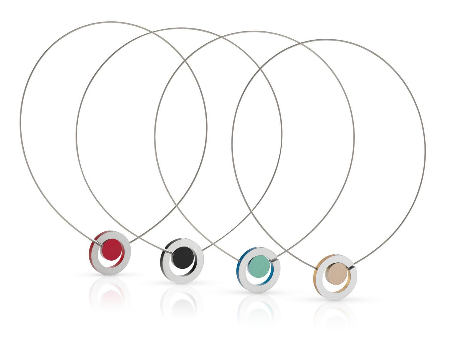 Vier minimalistische kettingen: rode, zwarte, blauwgroene en bruine cirkels in zilveren ringen, aan dunne zilveren koorden.