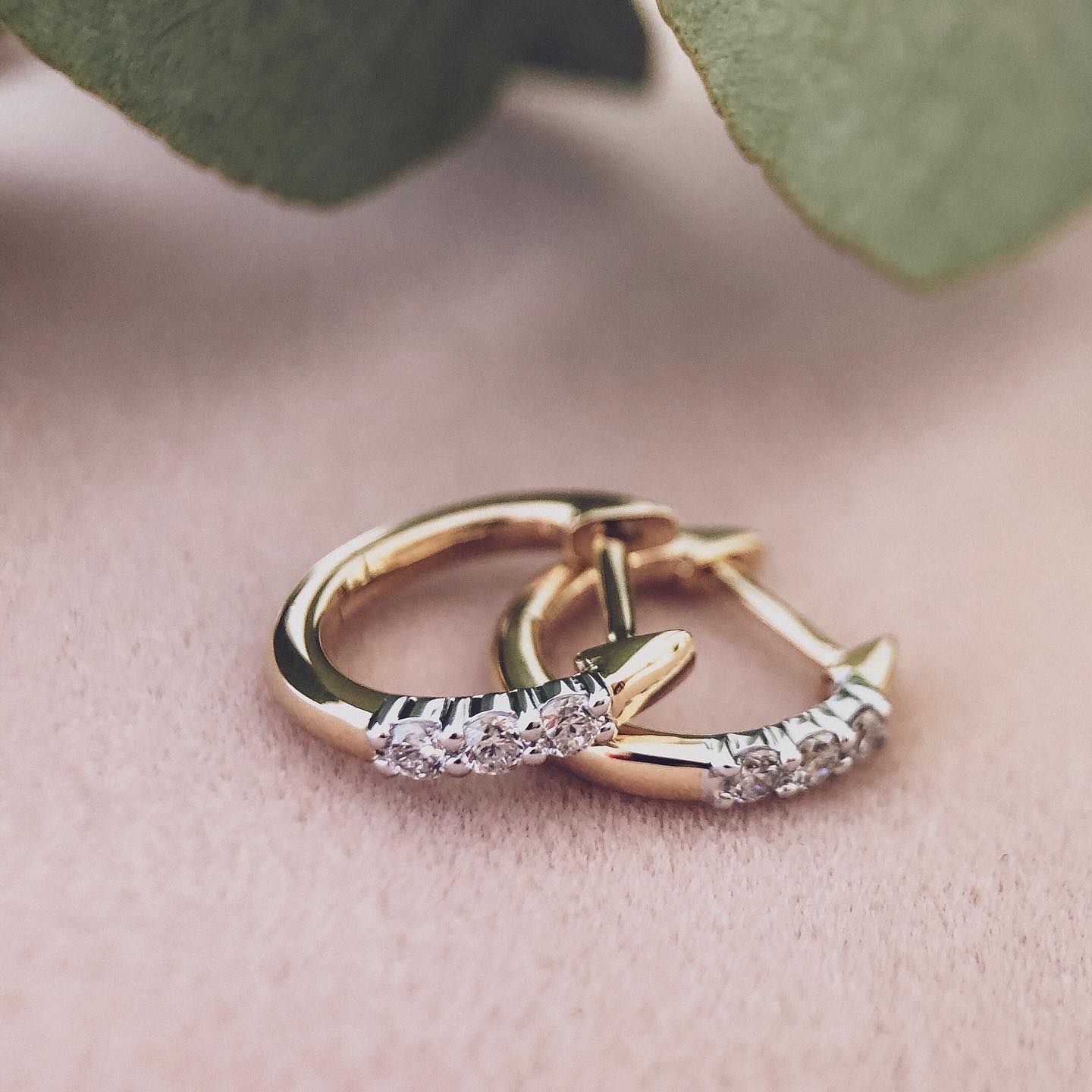 Gouden creolen met kleine diamantjes op een roze ondergrond.