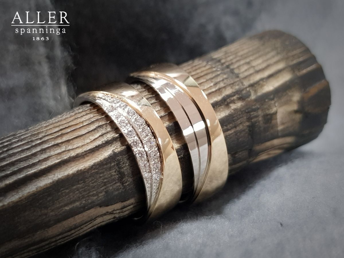 Drie gouden ringen met diamanten op een houten oppervlak.