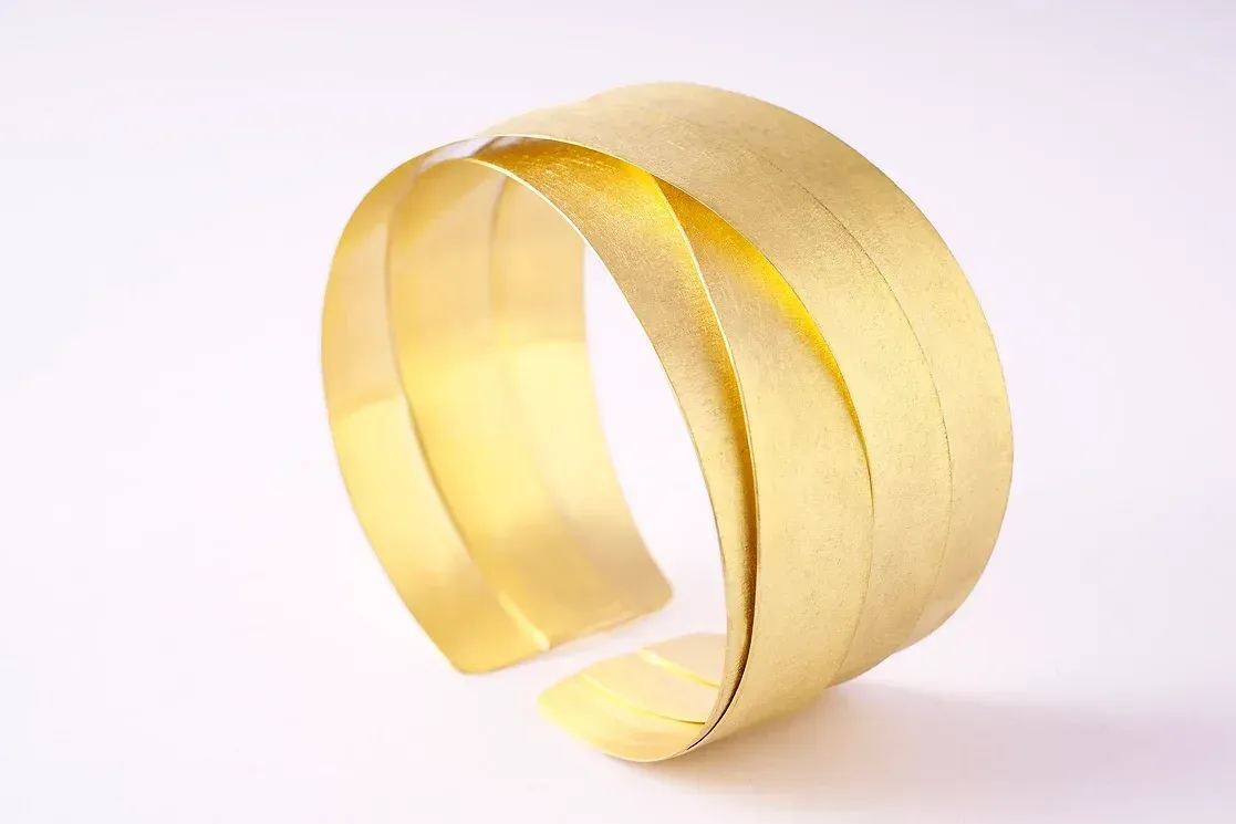 Gouden armband met een vloeiend, gelaagd design.