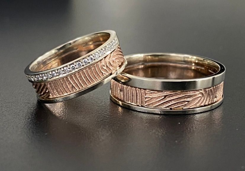 Twee trouwringen: één met diamanten, beide met getextureerde roségouden banden en zilveren randen.