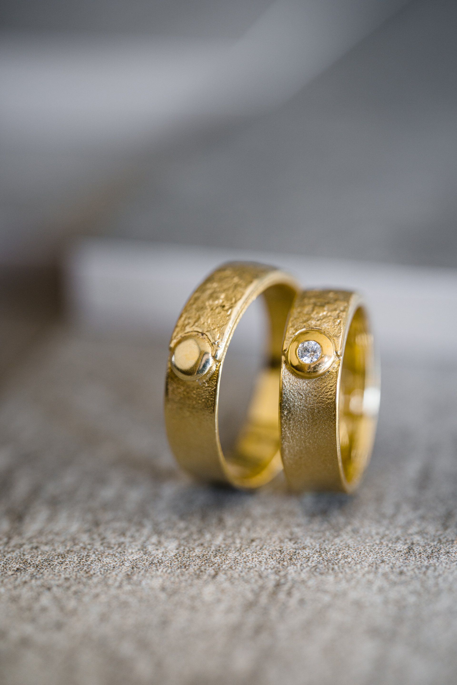 Twee gouden trouwringen met getextureerde banden en kleine edelstenen.