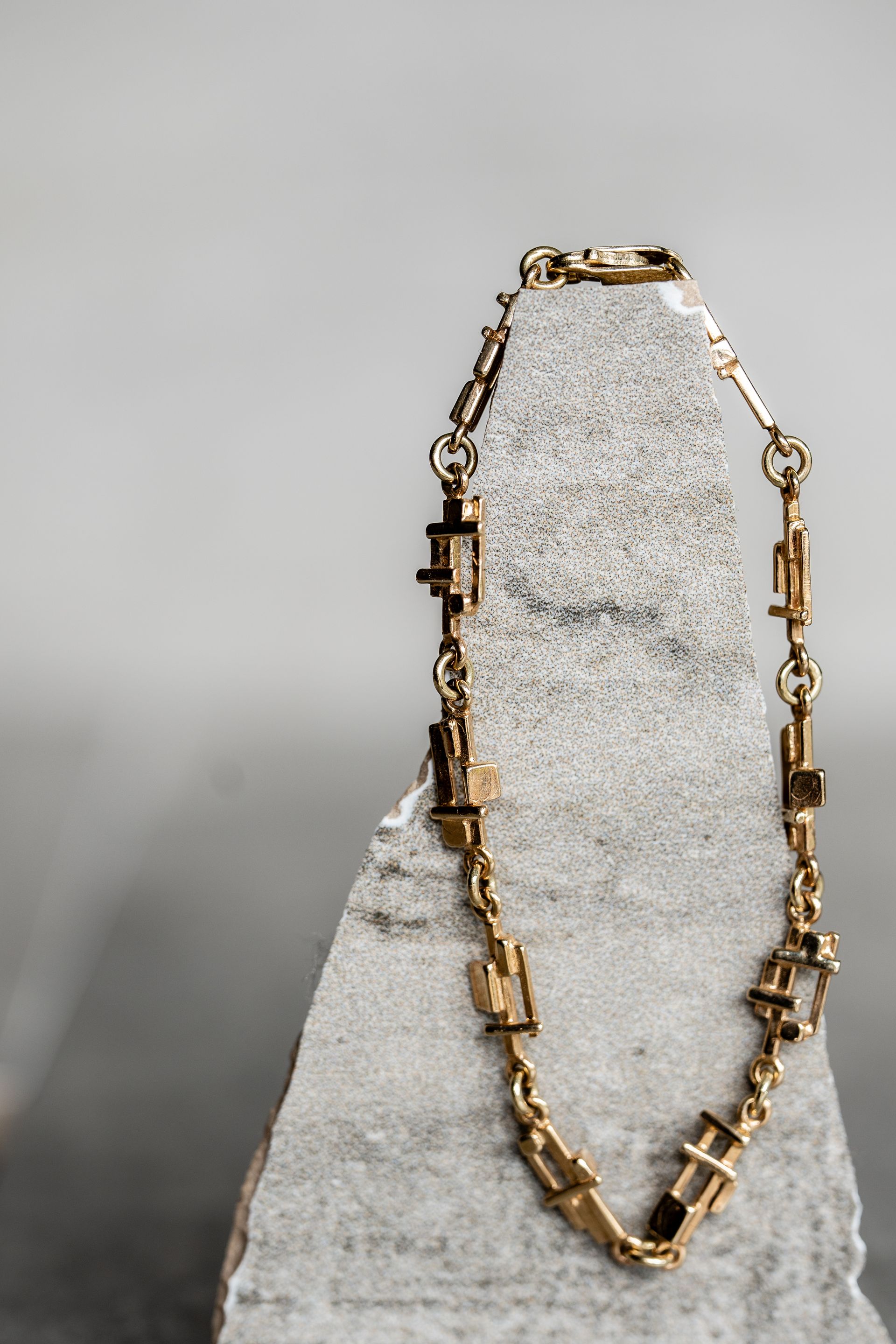 Gouden ketting gedrapeerd over een grijs-witte rots.