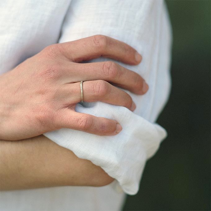 Hand met een dunne ring, rustend op een witte mouw.