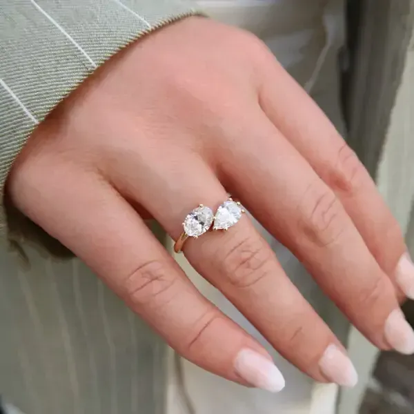 Goudkleurige oorbellen met een verweven design, aan één kant bezet met kleine heldere steentjes, op een witte achtergrond.