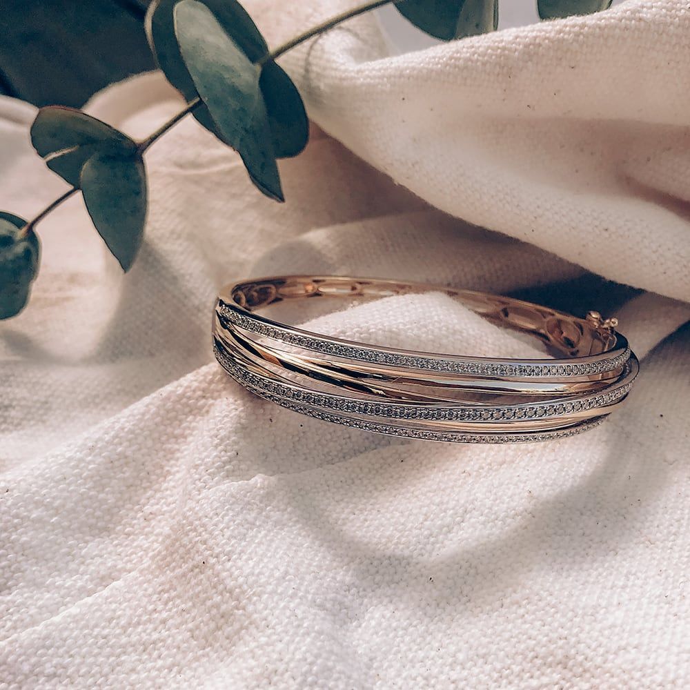 Vrouw draagt ​​een gelaagde gouden ketting met rode edelstenen en bijpassende oorbellen, bruin topje.