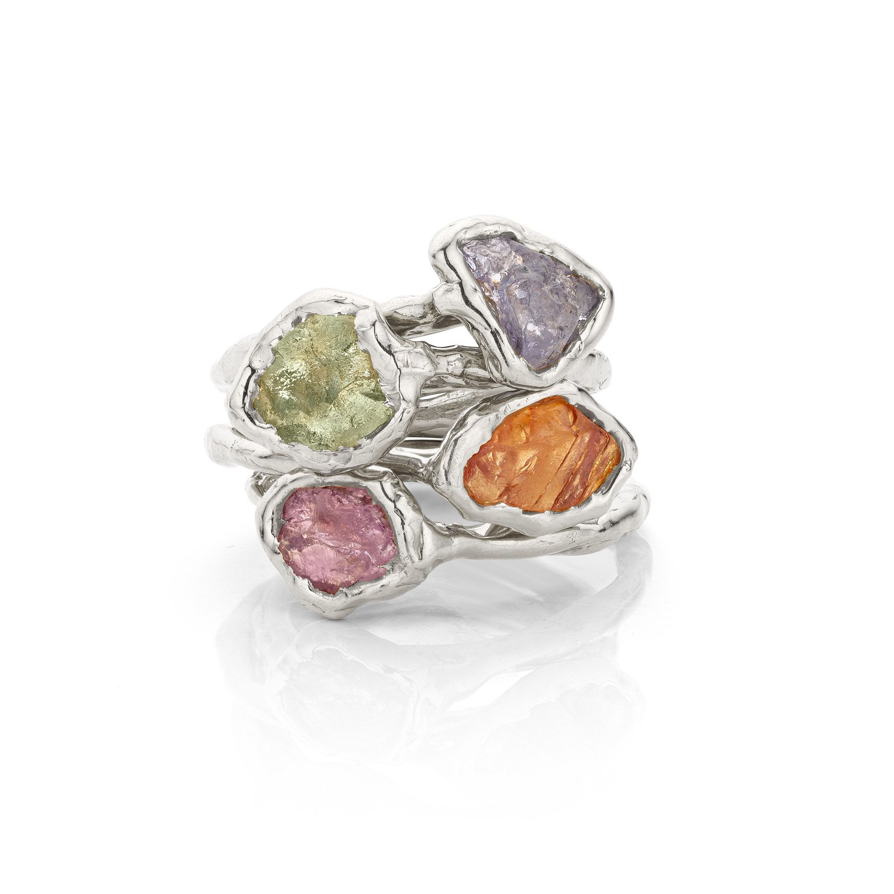 Stapel zilveren ringen, elk met een ruwe edelsteen in een andere kleur: groen, paars, oranje en roze.
