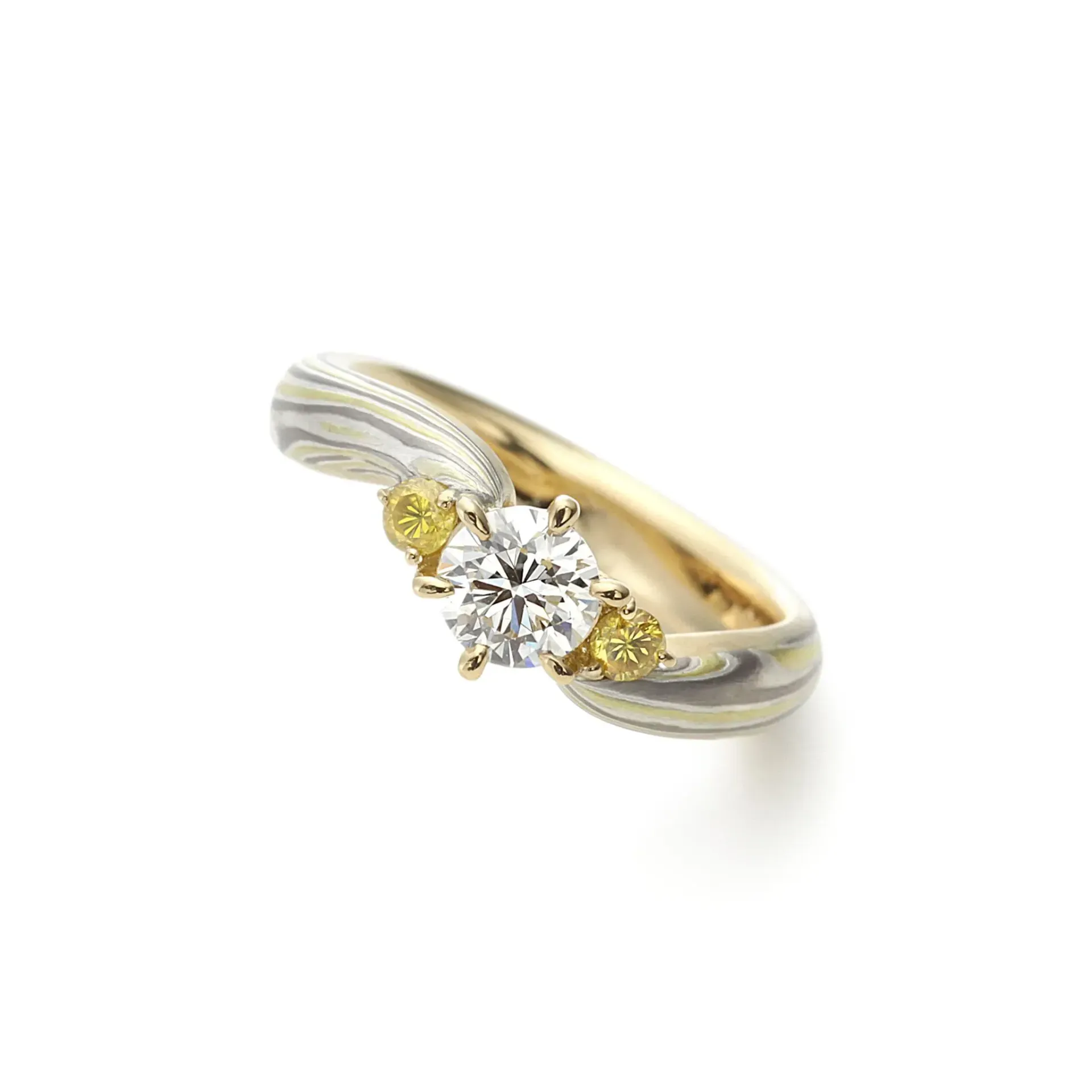 Verlovingsring met diamant, een grote middelste steen en twee kleinere gele stenen.