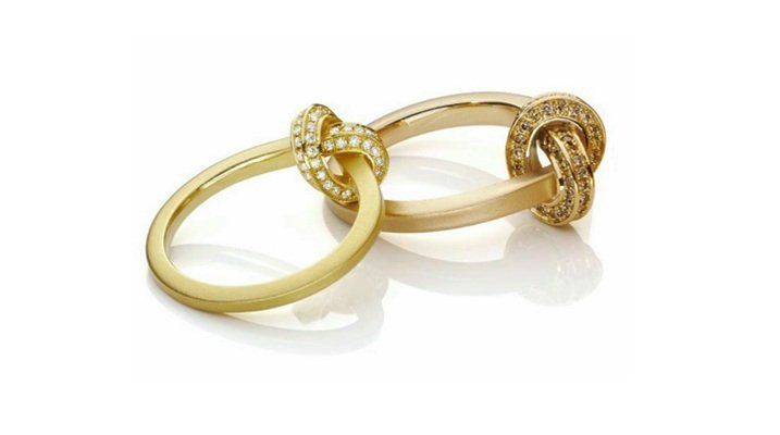 Twee gouden ringen, één glad, de andere geknoopt, beide met diamanten accenten.