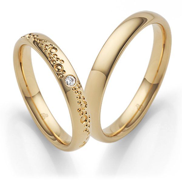 Twee gouden trouwringen, waarvan één met een kleine diamant en een structuurmotief.