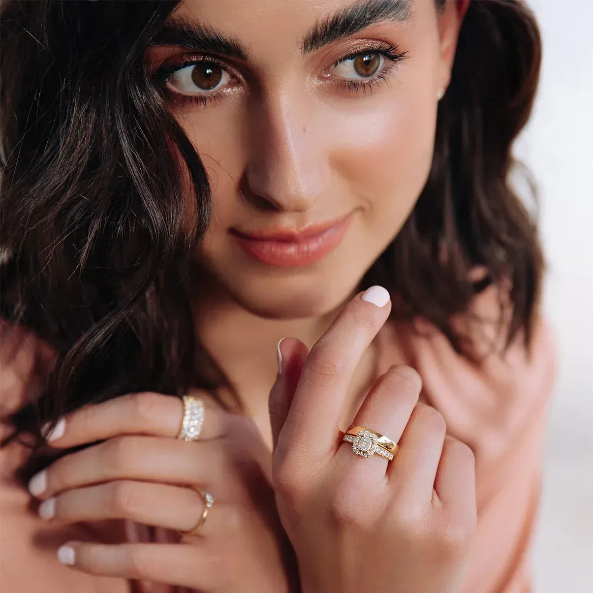 Vrouw met donker haar, kijkend naar haar hand, pronkend met haar ringen.