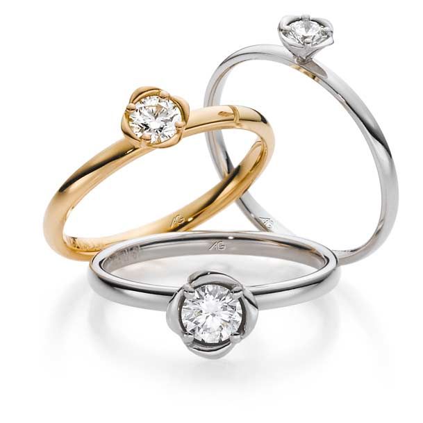 Drie solitaire diamanten ringen in goud en zilver, met bloemvormige zetting.