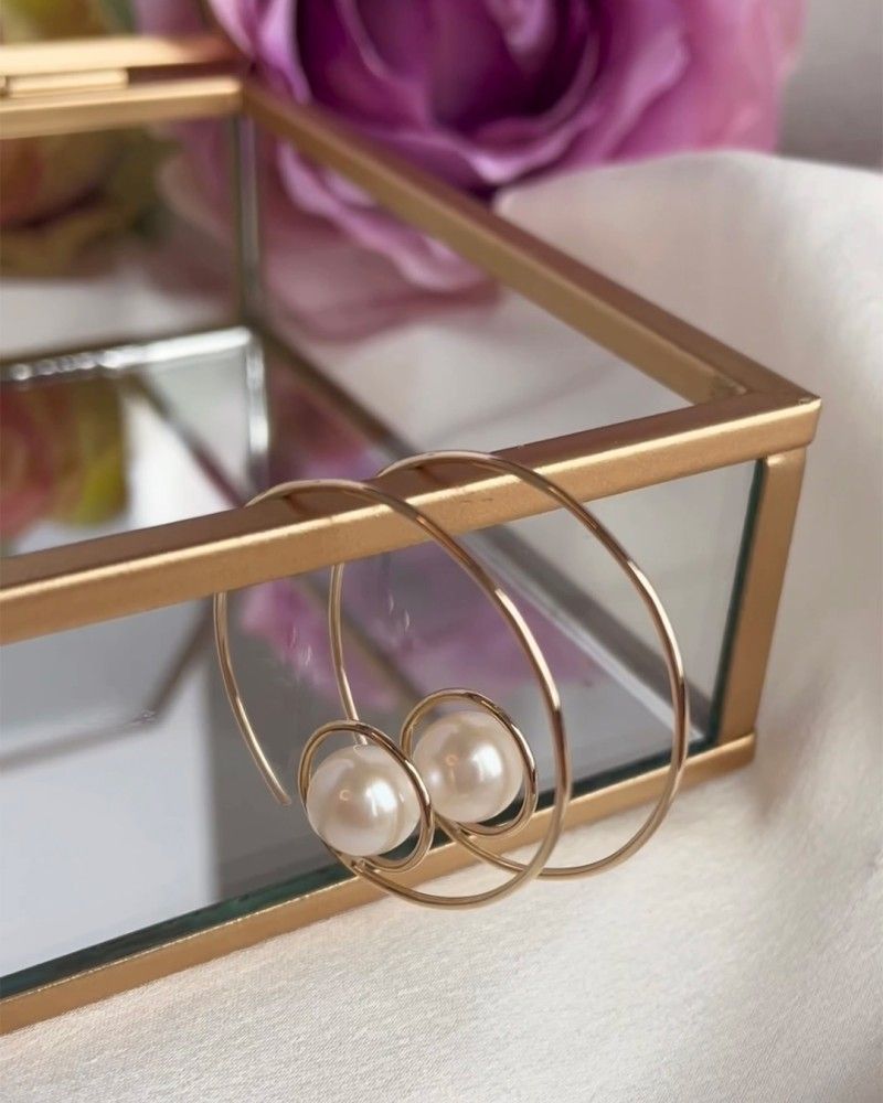 Goudkleurige oorbellen met een verweven design, aan één kant bezet met kleine heldere steentjes, op een witte achtergrond.
