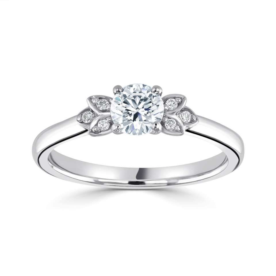 Verlovingsring met diamant, een ronde middensteen en bladvormige zijstenen op een witte band.