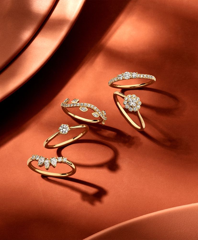 Gouden ringen met diamanten op een reflecterend koperen oppervlak.