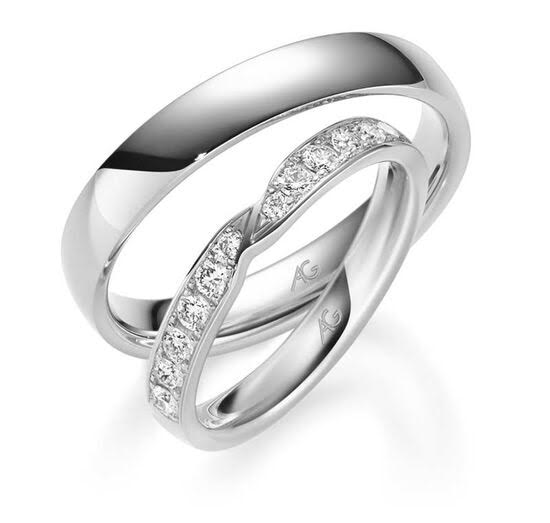Twee zilveren trouwringen: één eenvoudig en één met in een gebogen patroon ingelegde diamanten.