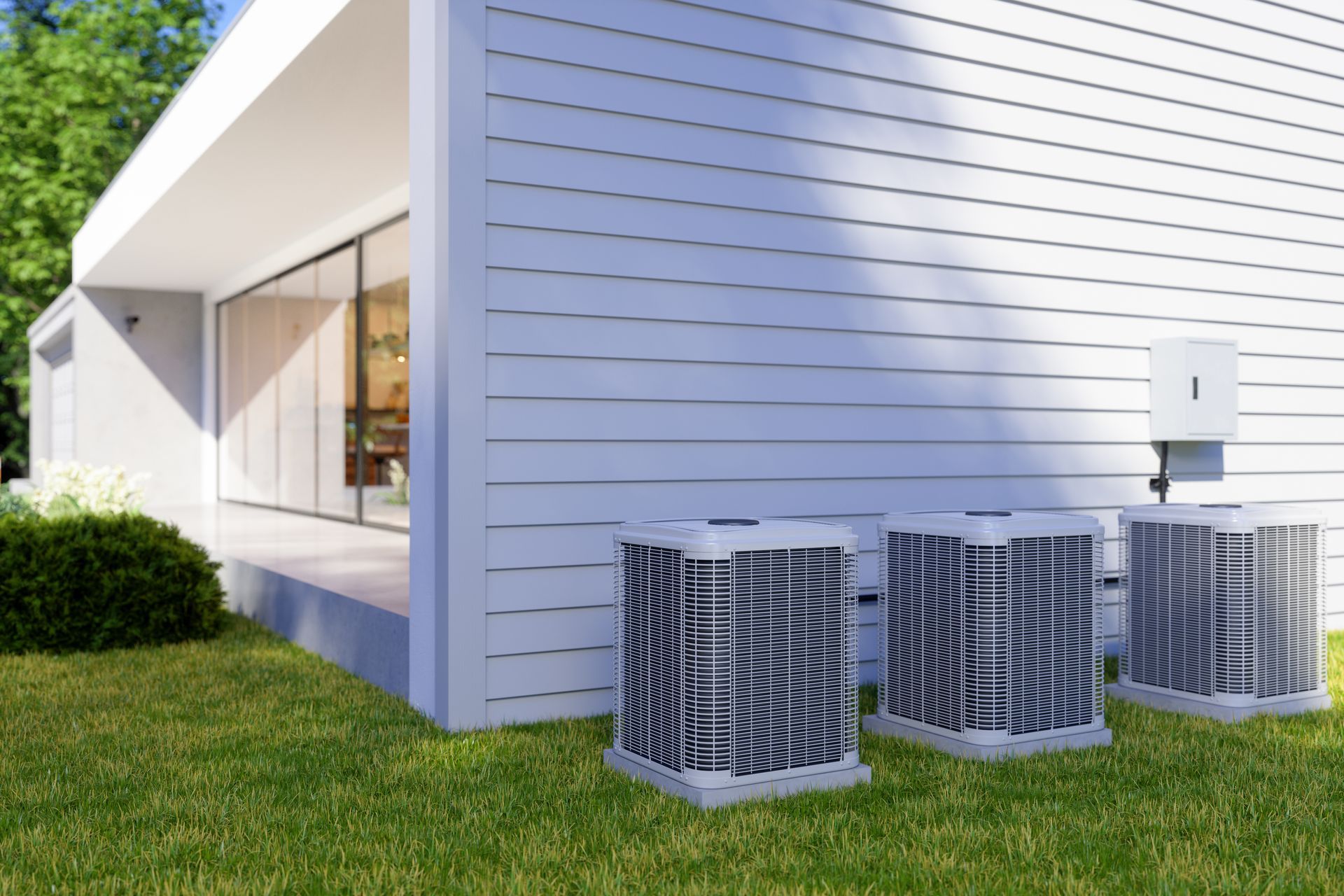 Three air conditioning units next to a white house with a glass door. Green grass and trees surround.