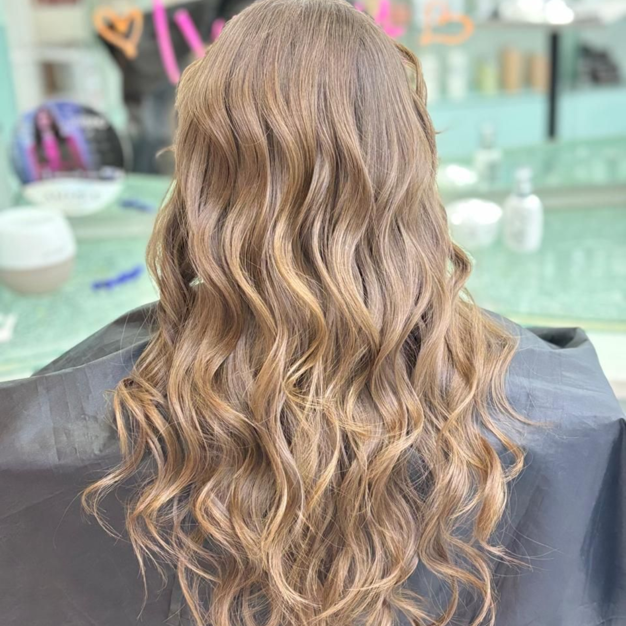 Cabello rubio largo y ondulado peinado en rizos sueltos en una silla de peluquería.