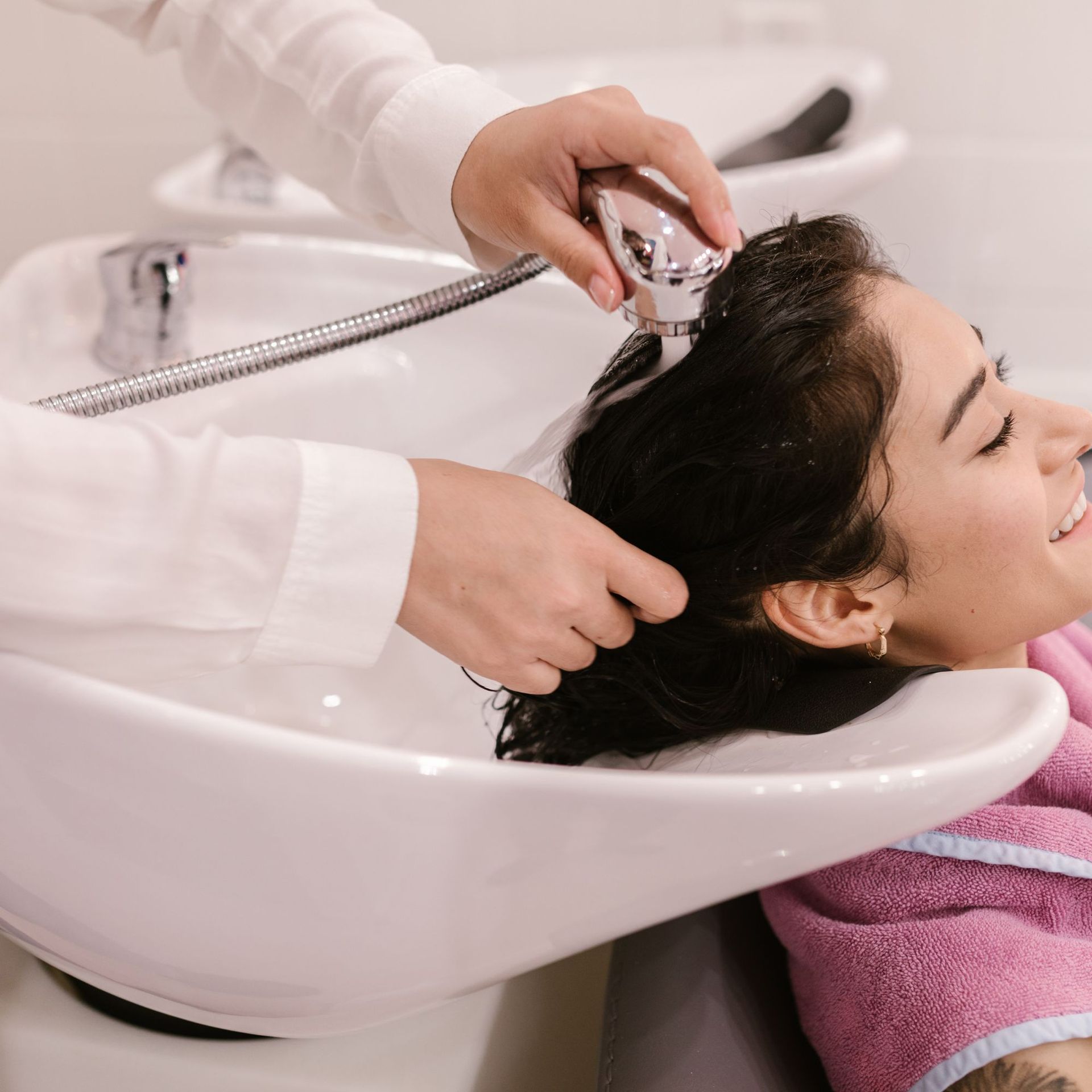 Enjuagando el cabello en un lavabo de peluquería con una alcachofa de mano.