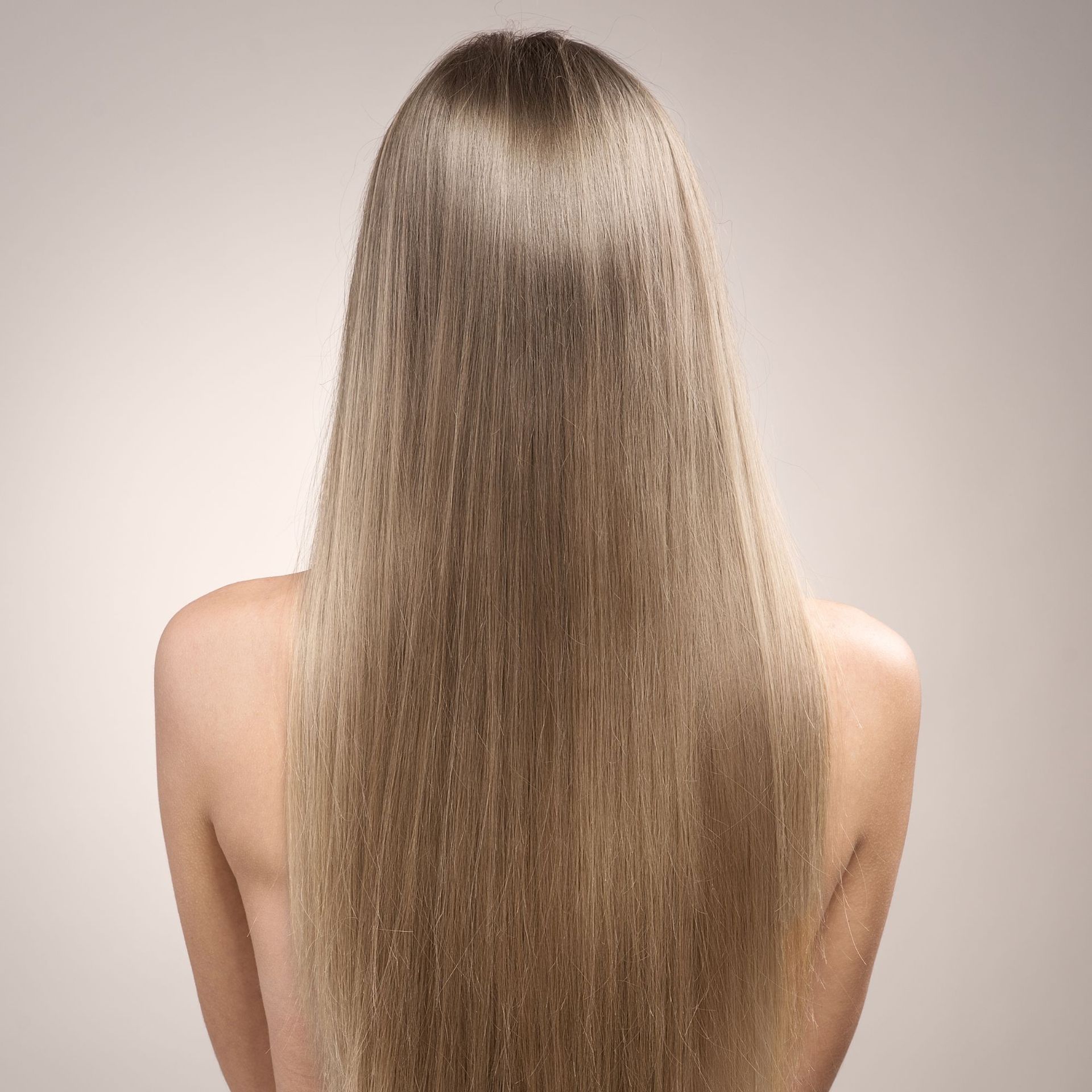 Vista trasera de una persona con cabello largo, liso y castaño claro sobre un fondo neutro.