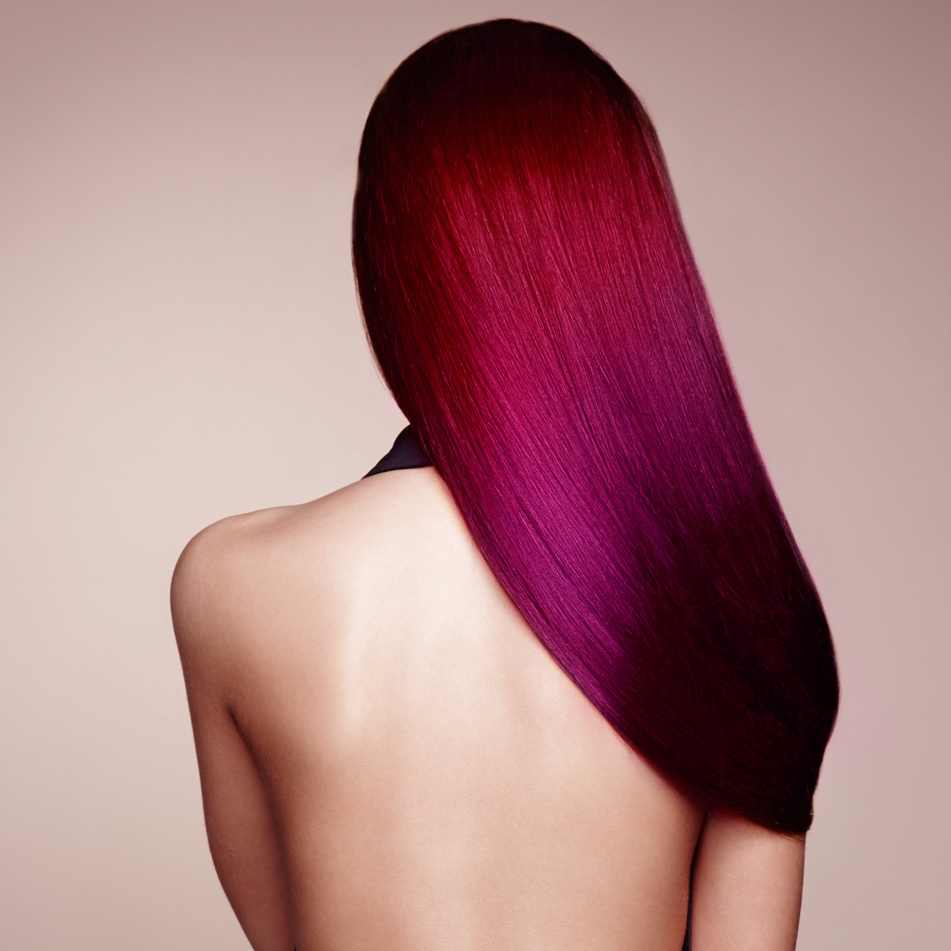 Persona vista de espaldas con cabello largo y liso de color magenta sobre un fondo neutro.
