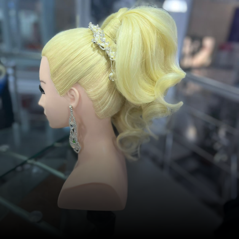 Cabeza de maniquí rubia con coleta alta, diadema con joyas y pendientes colgantes en un salón de belleza.