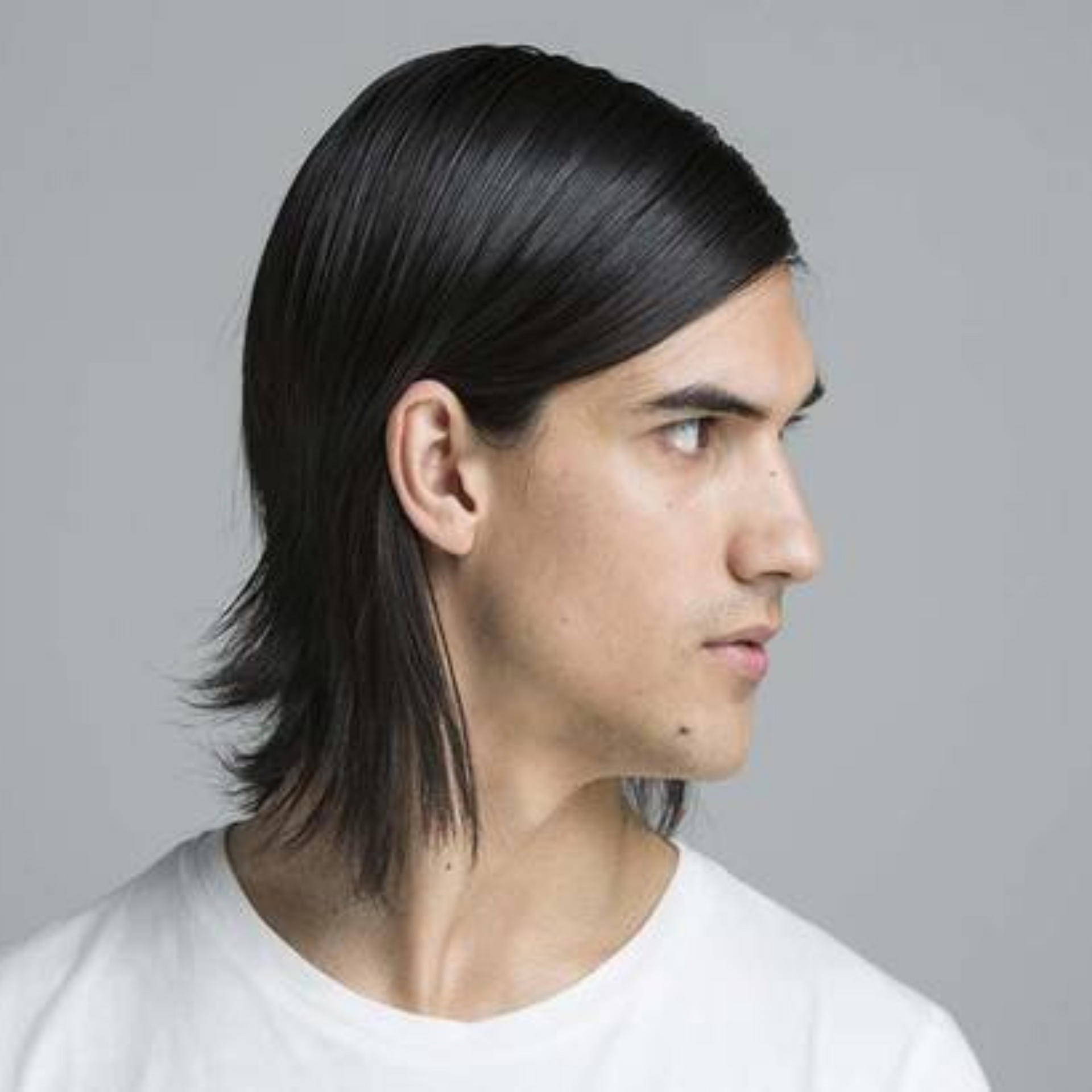 Perfil de una persona con cabello largo y oscuro sobre un fondo gris, que viste una camisa blanca.