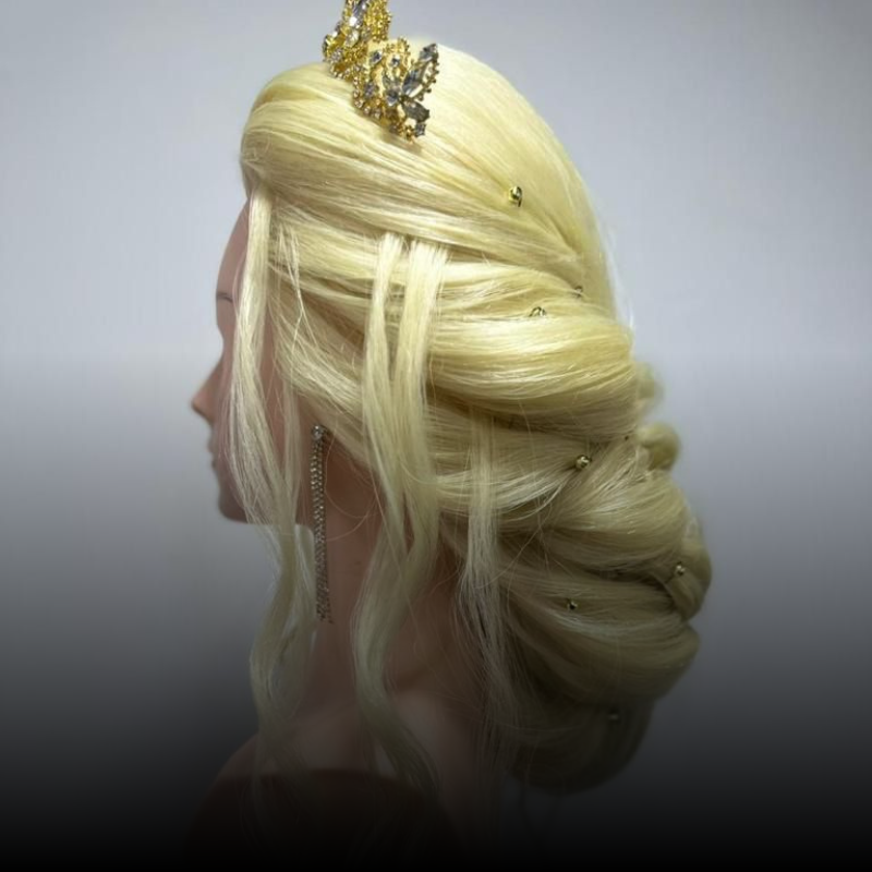Cabello rubio peinado en un elegante recogido con mechones sueltos, mostrado de perfil sobre un fondo gris liso.