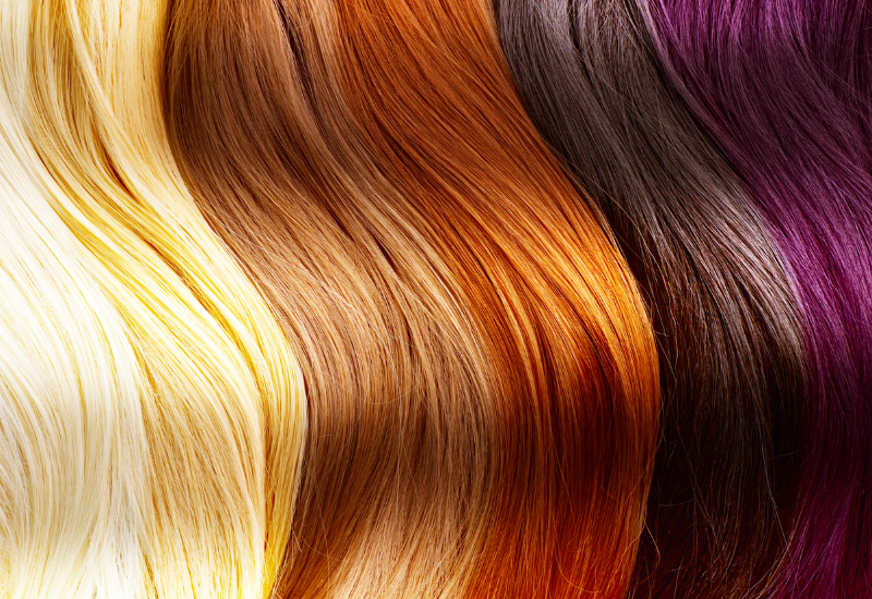 Primer plano de mechones de cabello ondulados y sueltos en tonos rubios, cobrizos, castaños y morados.
