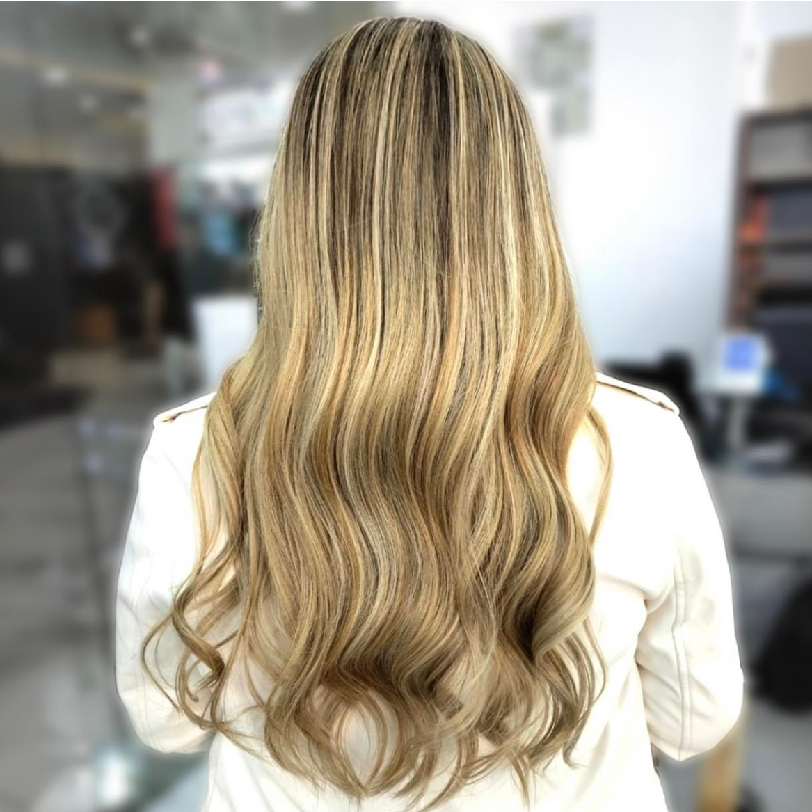 Vista posterior de una larga melena rubia ondulada en un salón de belleza.