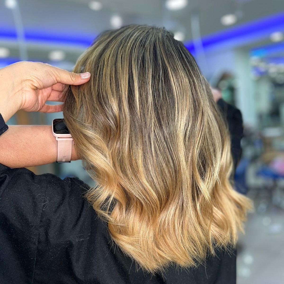 Peinado de corte bob rubio corto y ondulado en un salón de belleza.