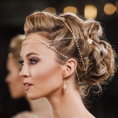Perfil de una mujer elegante con un elaborado recogido y un tocado dorado en un evento formal.