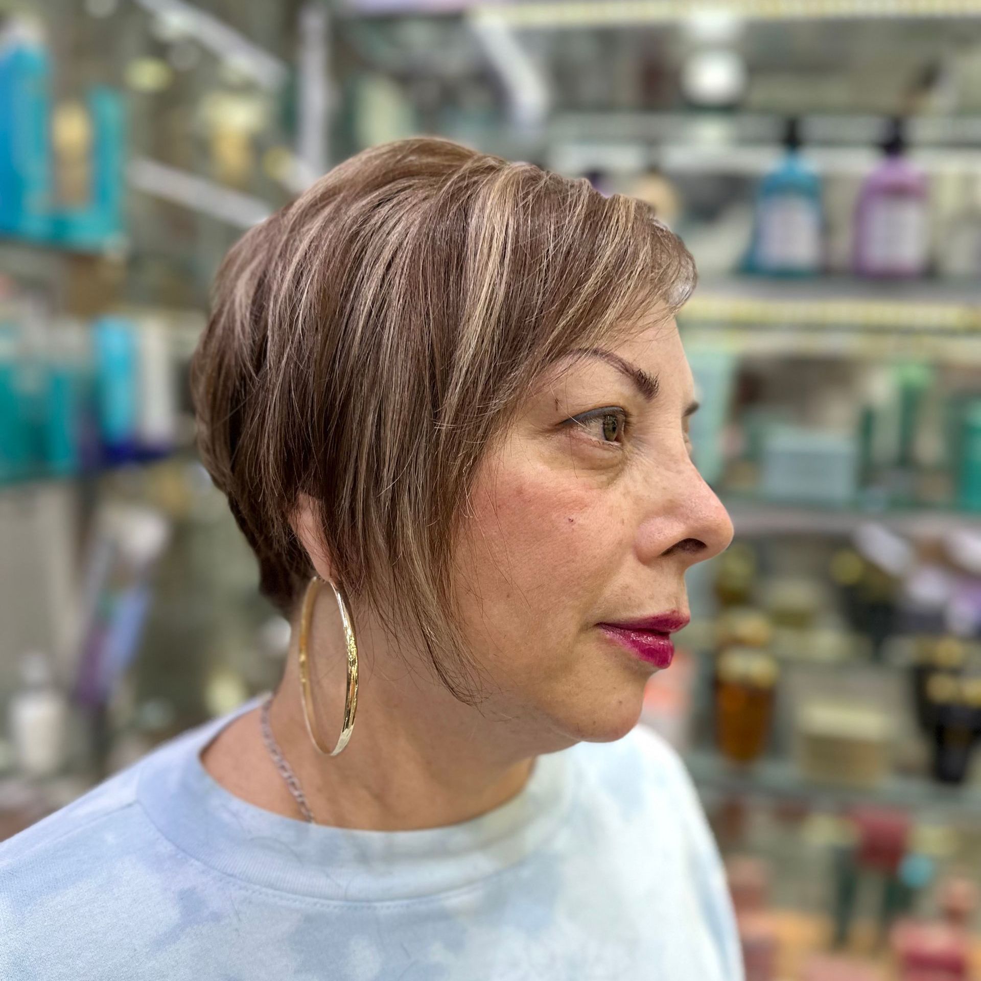 Vista de perfil de una mujer con cabello castaño corto en el pasillo de una tienda, mirando hacia la derecha.