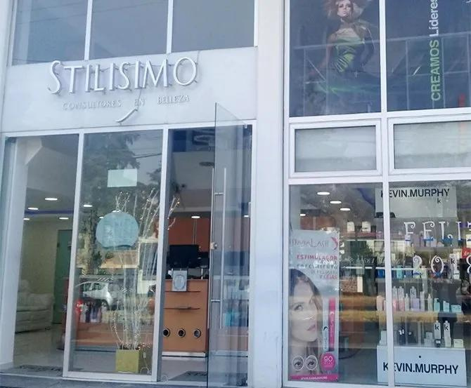 Fachada del salón de belleza STILISMO con ventanas de cristal y expositores de productos.