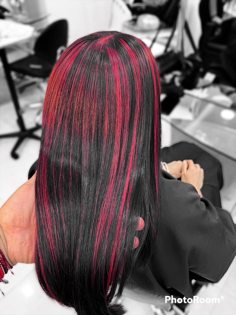 Cabello largo y negro con reflejos rojos, visto desde atrás en una silla de peluquería.