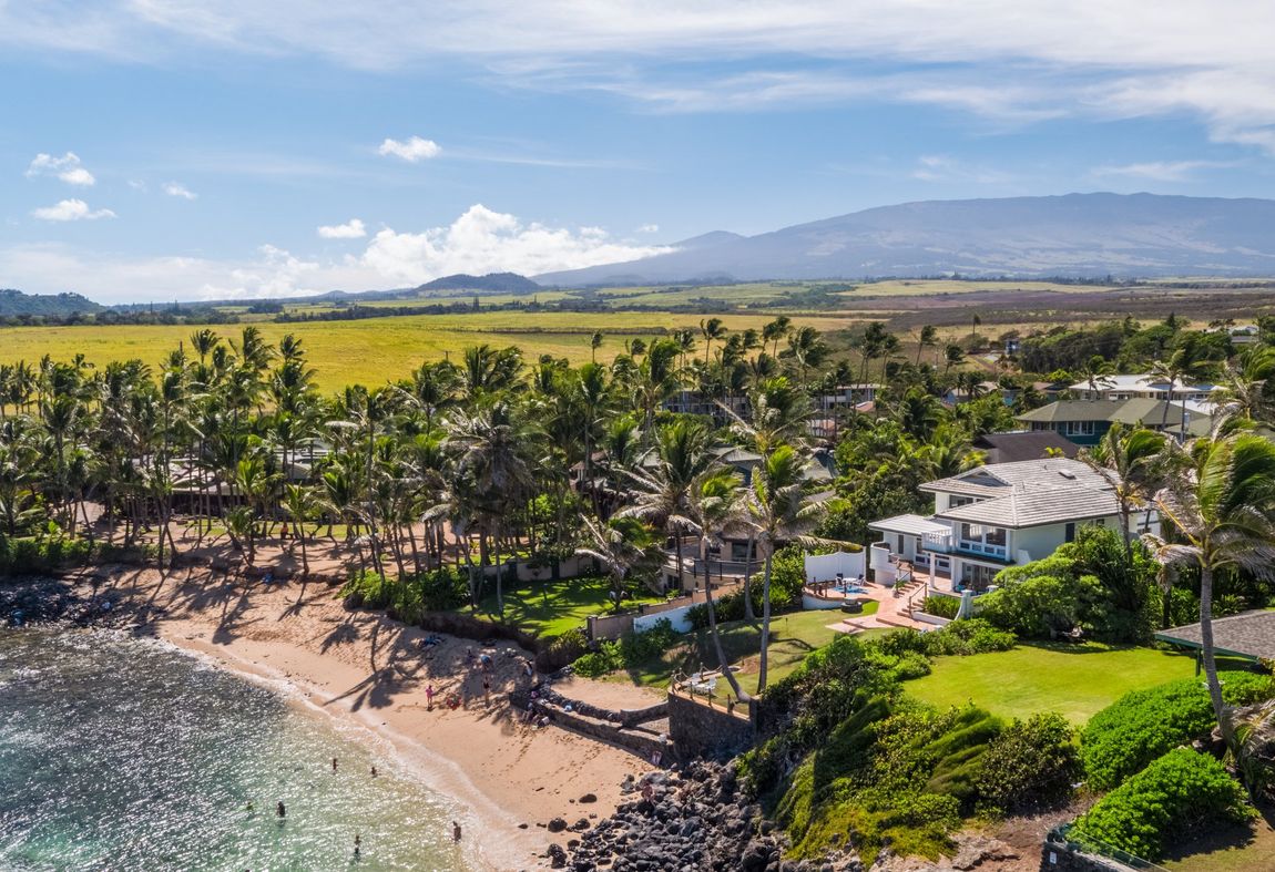 An aerial view of a beach with a house in the background.