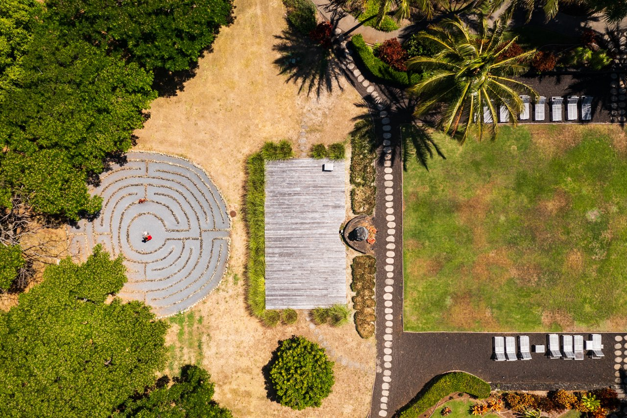 An aerial view of a park with a labyrinth and palm trees.